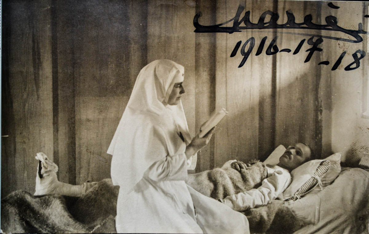 Regina Maria citind unui rănit, pe patul de spital din Coțofenești, noiembrie 1917 <br /> Sursă foto: Arhivele Naționale ale României
